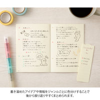 Notebook with handwritten notes and illustrations on a wooden surface with a pen and coffee cup.